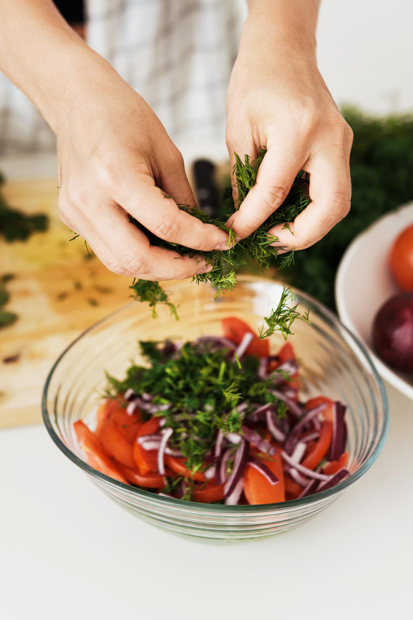 Hands arranging a seasonal salad on table